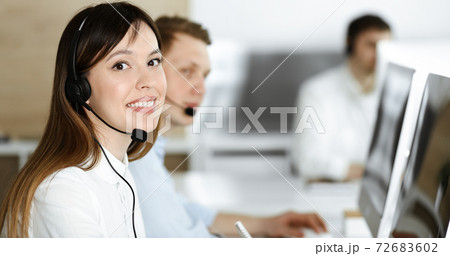 Group of diverse operators at work in call center. Beautiful asian woman sitting in headset at customer service office. Business concept 72683602