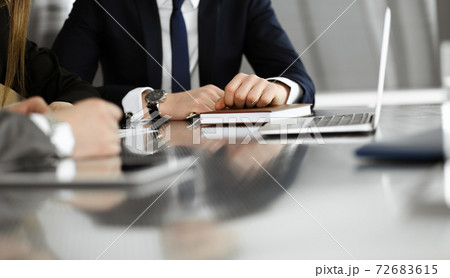 Unknown businessmen and woman sitting, working and discussing questions at meeting in modern office, close-up 72683615