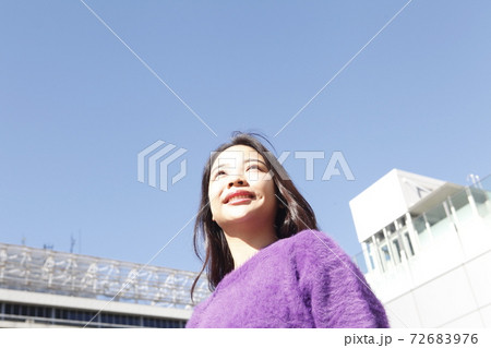 青空と上を向く笑顔の若い女性 72683976