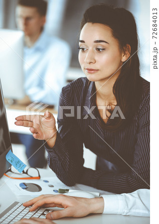 Business woman and man discussing questions while using computer at workplace in modern office. Teamwork, meeting and brainstorming concept 72684013