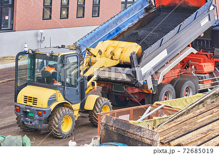 ダンプカーに積まれたアスファルトをタイヤショベルで運ぶ作業 72685019