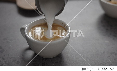 Pour steamed milk into espresso to make cappuccino on concrete countertop closeup Pour steamed milk into espresso to make cappuccino on concrete countertop closeup 72685157