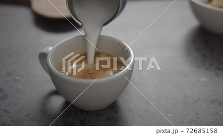 Pour steamed milk into espresso to make cappuccino on concrete countertop closeup Pour steamed milk into espresso to make cappuccino on concrete countertop closeup 72685158