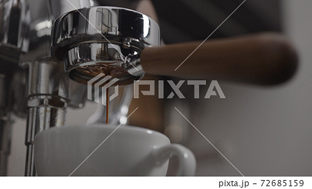 Low angle shot of coffee extraction with naked portafilter into cappuccino cup 72685159