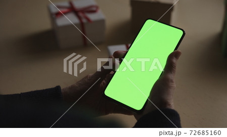 old female hands holding smartphone with green screen and celebrating holiday chatting with family old female hands holding smartphone with green screen and celebrating holiday chatting with family 72685160