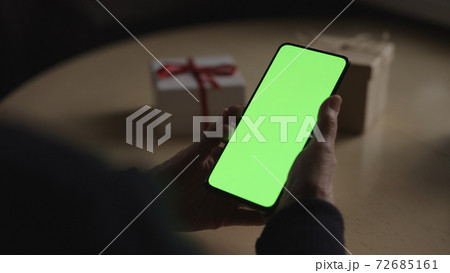 old female hands holding smartphone with green screen and celebrating holiday chatting with family old female hands holding smartphone with green screen and celebrating holiday chatting with family 72685161
