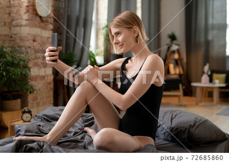 Happy young blond woman in black leotard making selfie or recording new video Happy young blond woman in black leotard making selfie or recording new video 72685860