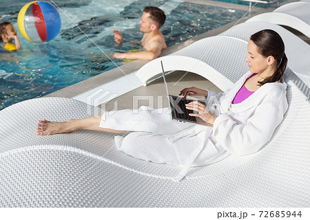 Young man and cute little girl playing in swimming pool while woman using laptop Young man and cute little girl playing in swimming pool while woman using laptop 72685944