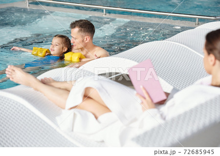 Young man supporting his little daughter in safety sleeves during swimming Young man supporting his little daughter in safety sleeves during swimming 72685945