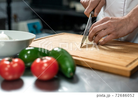 Hands of young male chef of modern restaurant chopping fresh vegetables Hands of young male chef of modern restaurant chopping fresh vegetables 72686052