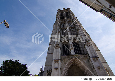 Mechelen, Belgium, August 2019. The imposing cathedral features a 97-meter bell tower in Gothic style. Beautiful summer day with blue sky. Mechelen, Belgium, August 2019. The imposing cathedral features a 97-meter bell tower in Gothic style. Beautiful summer day with blue sky. 72687366