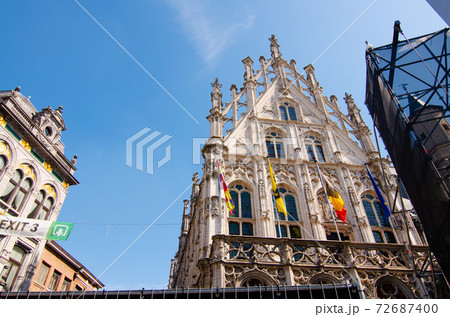 Mechelen, Belgium, August 2019. The town hall overlooks the large square, the Grote Markt. It stands out for the elegance of the facade and the flags. In the square they are setting up a stage 72687400