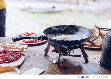 Frying scrambled eggs in the mountains. Tourist woman preparing delicious tourist breakfast outdoors. Frying scrambled eggs in the mountains. Tourist woman preparing delicious tourist breakfast outdoors. 72687908