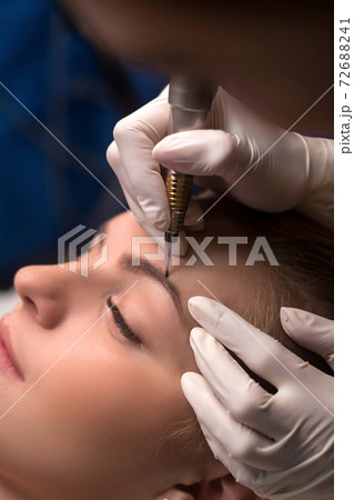 Permanent eyebrow makeup. Cosmetologist applying tattooing of eyebrows. 72688241