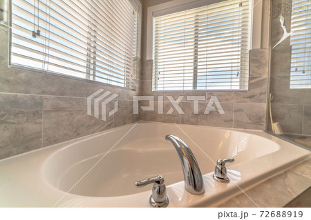 Clean built in bathtub with shiny faucet inside the bathroom of a home Clean built in bathtub with shiny faucet inside the bathroom of a home 72688919