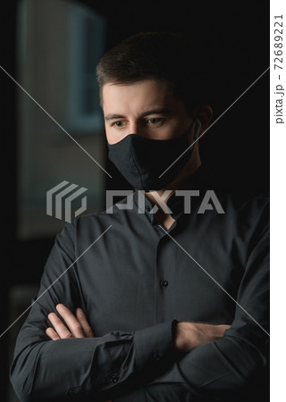 Portrait of a brunette in a black shirt in a black face mask. Black face mask during the pandemic corona virus. Portrait of a brunette in a black shirt in a black face mask. Black face mask during the pandemic corona virus. 72689221