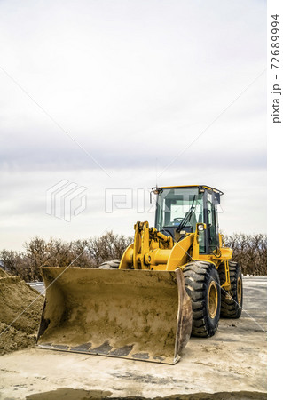 Focus on a yellow bulldozer with dirty bucket and wheels at a construction site Focus on a yellow bulldozer with dirty bucket and wheels at a construction site 72689994