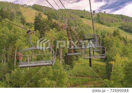 Vibrant green summer landscape of trees and mountain beneath chairlifts 72690088