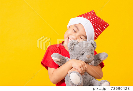 little boy smiling hugging teddy bear, Kid dressed in Santa Claus hat little boy smiling hugging teddy bear, Kid dressed in Santa Claus hat 72690428