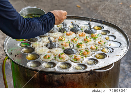 Woman hand cooking Vietnamese tiny fried shrimp pancake on skillet 72693044