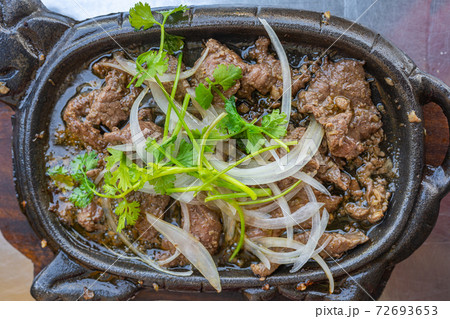 Sizzling beef fillet on iron platter with onion and coriander  72693653