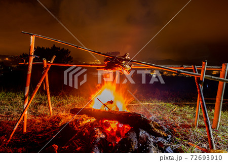 Grilled chicken on bonfire with orange flames and firewood 72693910