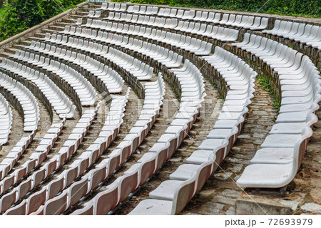 White plastic chairs in rows at outdoor stadium 72693979