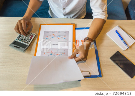 Close up of businessman using calculator to check financial data Close up of businessman using calculator to check financial data 72694313