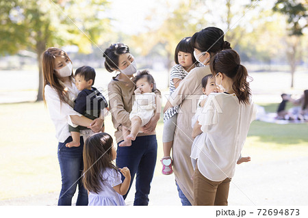 公園で遊ぶマスク姿のママ友と子供の写真素材