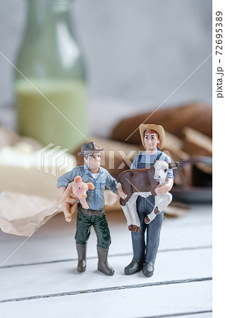 Small models farmers with sliced bread with a milk and butter on a on natural wooden board. Rustic style. Small models farmers with sliced bread with a milk and butter on a on natural wooden board. Rustic style. 72695389