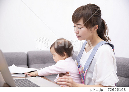 パソコンを使う疲れた主婦と赤ちゃんの写真素材