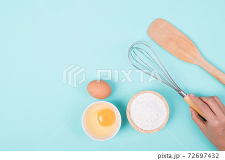 Hand holding whisk with flour and egg for bakery cooking 72697432