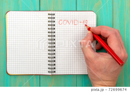 Hand writing a word COVID-19 with red pencil on a 72699674
