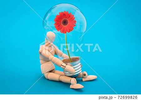 Wooden man holds a light bulb with red flower Wooden man holds a light bulb with red flower 72699826