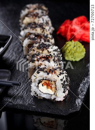Japanese sushi on a dark stone background. Sushi set with ginger, wasabi and soy sauce. Serve with chopsticks. Japanese sushi on a dark stone background. Sushi set with ginger, wasabi and soy sauce. Serve with chopsticks. 72700713