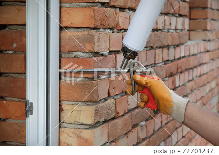 Worker using  polyurethane foam to fix door 72701237