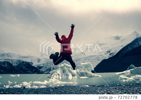 Cheering woman hiker jumping face the glacier lagoon in winter Cheering woman hiker jumping face the glacier lagoon in winter 72702778
