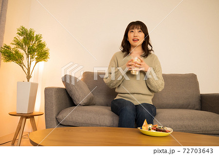 ポップコーンを持ちながらテレビを楽しむ女性 72703643