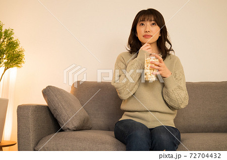 心配そうにテレビに見入る女性 72704432