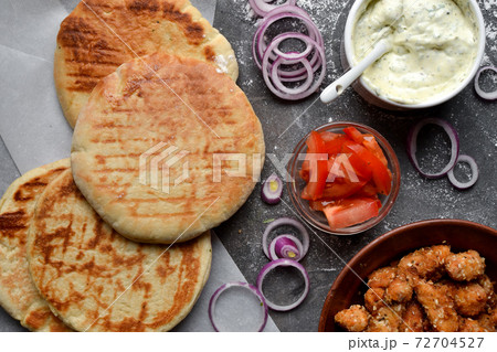 Ingredients for making pita with chicken. Healthy fast food. Top view. Dark background. Tomatoes, red onion, chicken nuggets. Ingredients for making pita with chicken. Healthy fast food. Top view. Dark background. Tomatoes, red onion, chicken nuggets. 72704527