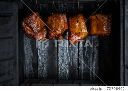 Close up of a smoked meat and belly or beech meat with dark crust in the smokehouse or smoker, food concept Close up of a smoked meat and belly or beech meat with dark crust in the smokehouse or smoker, food concept 72706402