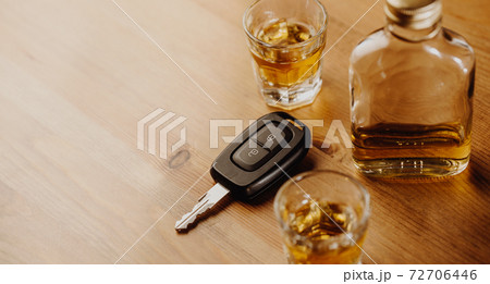 Close up of a car keys and very strong alcohol on the table, do not drink and drive concept Close up of a car keys and very strong alcohol on the table, do not drink and drive concept 72706446
