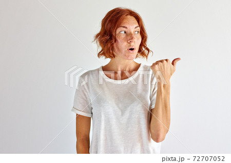 surprised young woman pointing finger at side, right surprised young woman pointing finger at side, right 72707052