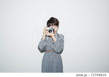 フィルムカメラのファインダーを覗く若い女性の写真素材