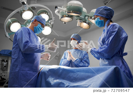 Medical team standing beside patient after successful surgery. 72709547
