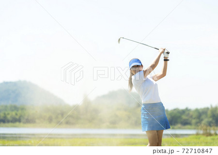 Golfer woman chip golf ball out of a sand trap. 72710847
