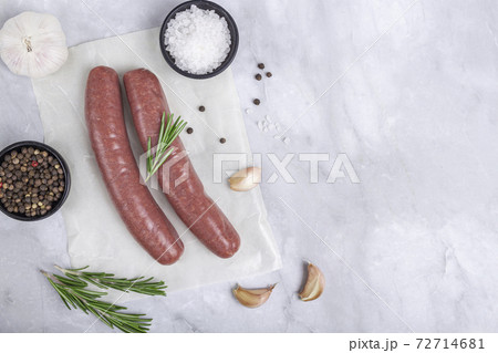 Raw meat beef sausages for grill and spicy, herbs rosemary, pepper, salt on table 72714681