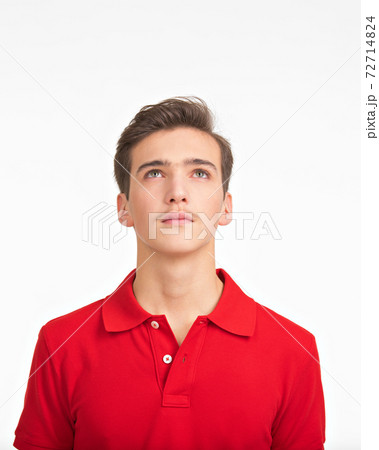 Photo of  young  confident man looking up. Portrait of handsome guy with a calm emotions looking up.  Teenager  lifts a head up. 72714824