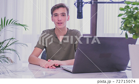 Man blogger videotapes his vlog at home. Teenage boy recording his video blog. Young man speaks in front of a video camera for his blog channel. Vlogger makes online streaming using smartphone 72715074