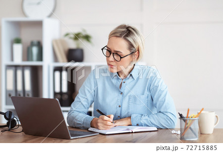 Focused woman writing down info during business training or online meeting, participating in web conference from home 72715885